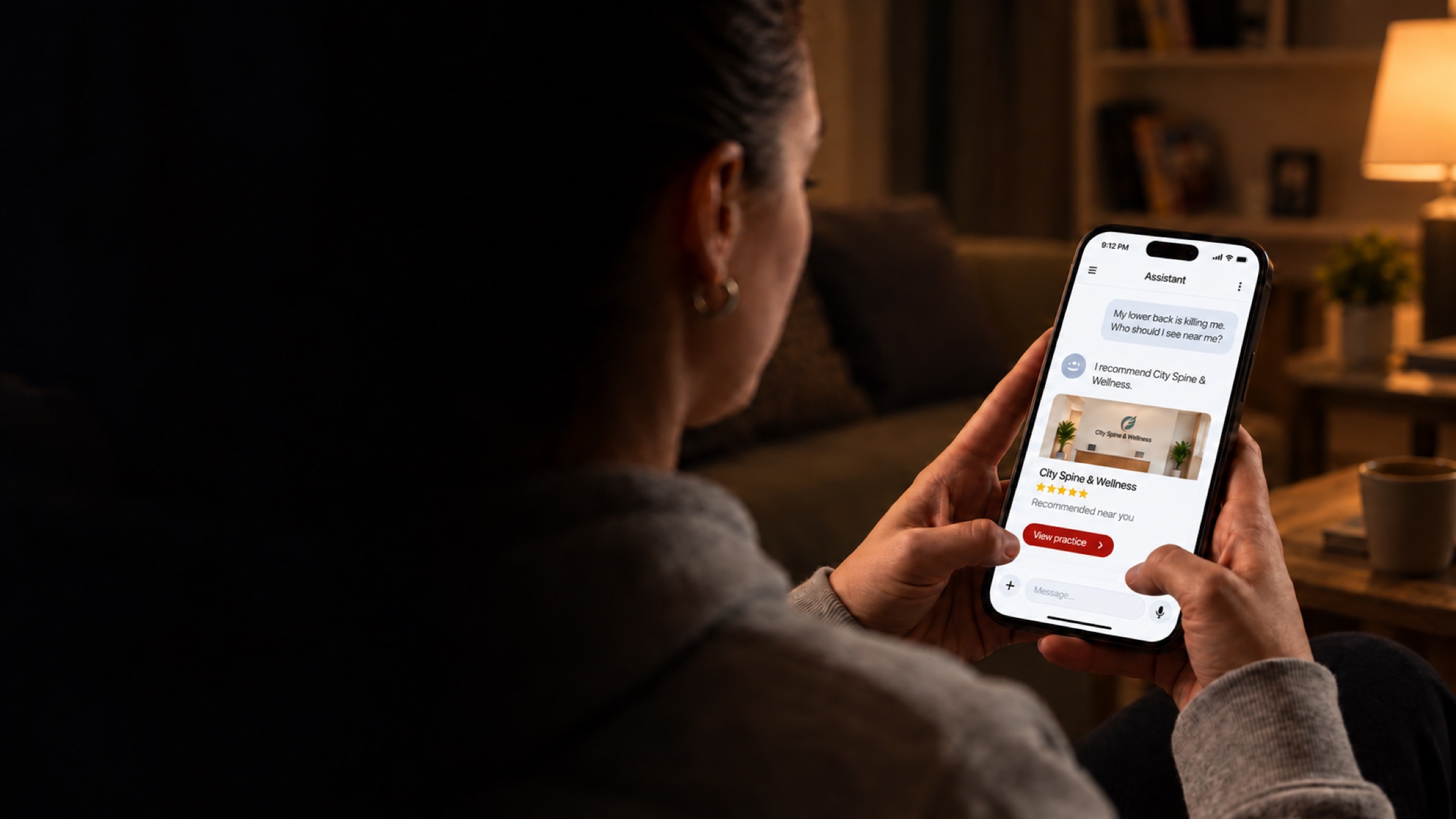 An illustration: at 9pm, a person in pain asks an AI assistant on their phone who to see for lower back pain, and it recommends a chiropractic practice.